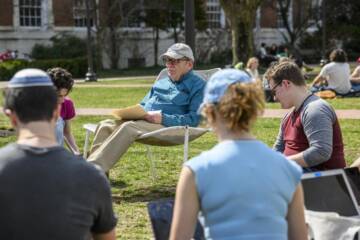 Professor Steven David and students sitting and talking on campus