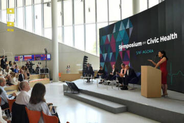 Attendees watch a speaker at a podium at SNF Agora event