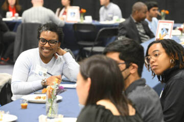 Smiling student at a table with other students